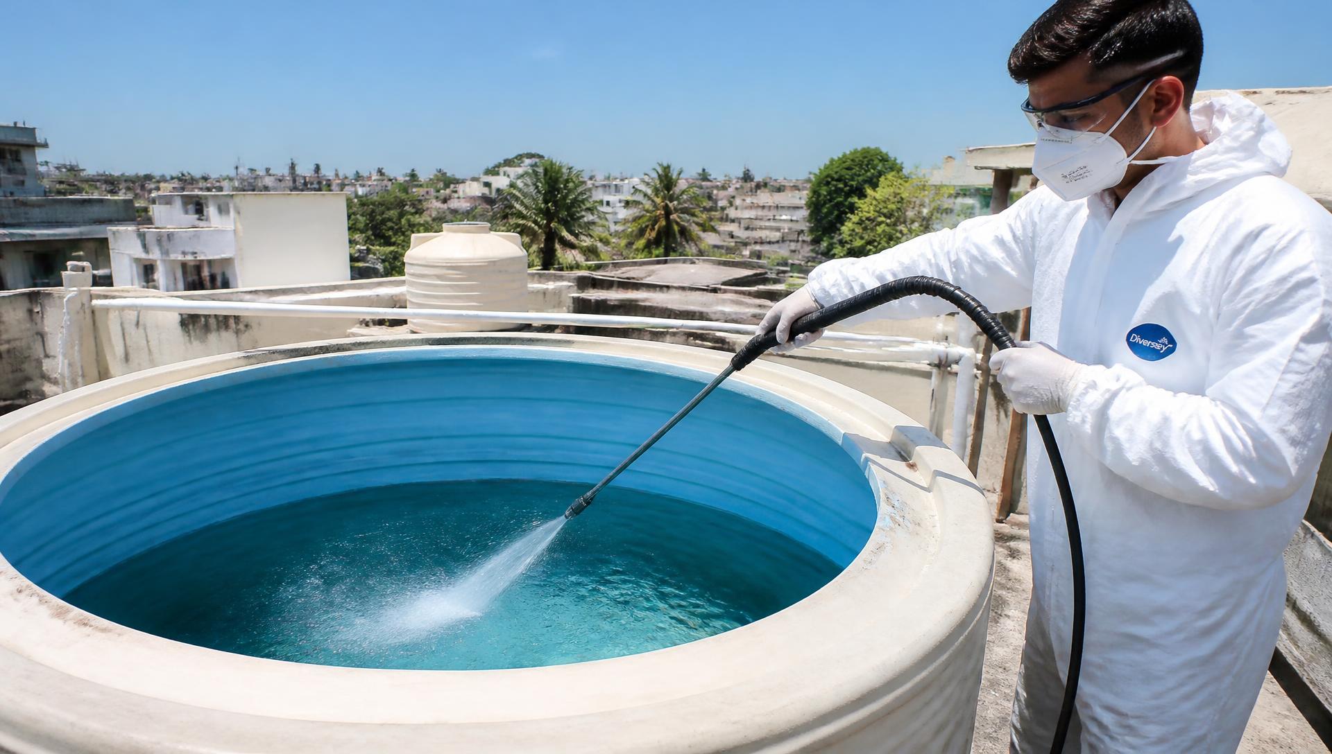 Profissional higienizando caixa d'água predial com equipamento de alta pressão
